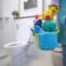 Person carrying floor cleaner liquid and tools in bathroom